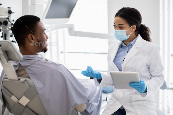 Black Dentist Lady With Digital Tablet In Hands Consulting Male Patient In  Clinic Stock Photo by Prostock-studio