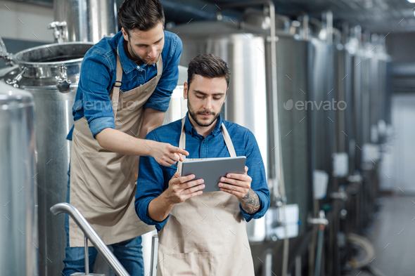 Men inspectors with digital tablet technician inspecting modern beer factory plant - Stock Photo - Images