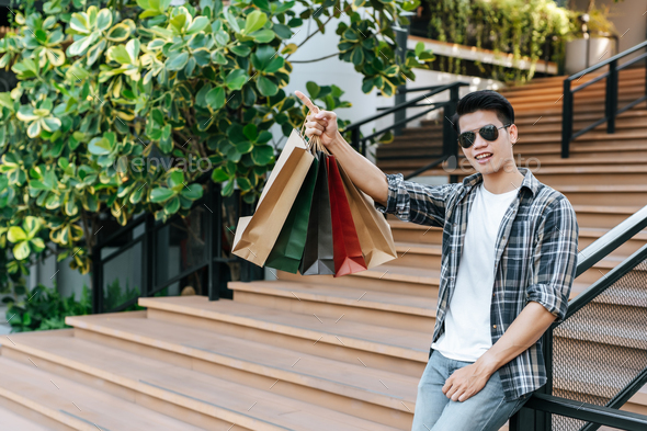 Handsome man in sunglasses with shopping bag at shopping mall