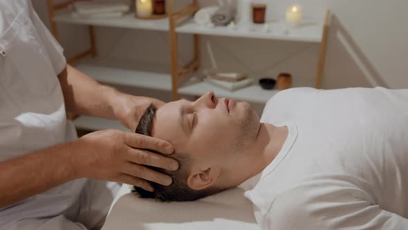 Young Man Relaxing During Professional Head Massage in SPA Salon