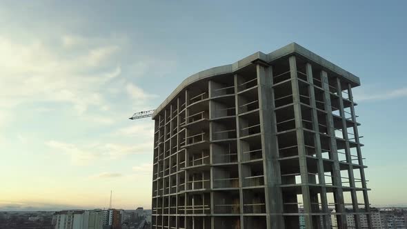 Aerial view of concrete frame of tall unfinished apartment building under construction in a city alt