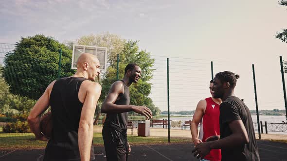 Four Young Sportsmen Basketball Players Hug and Shake Hands After the End of the Basketball Game alt