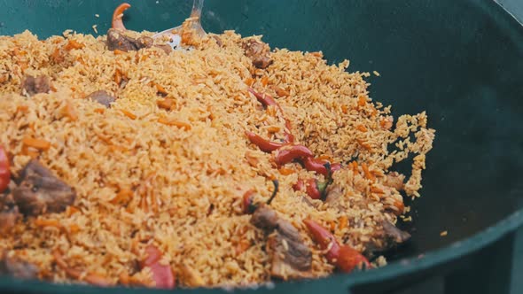 Big Vat with Cooked Pilaf or Rice Over an Open Fire. Street Food at the Party alt
