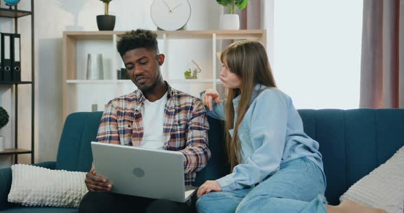 Friends Sitting Together on the Couch at Home and Talking while Watching Program on Computer alt