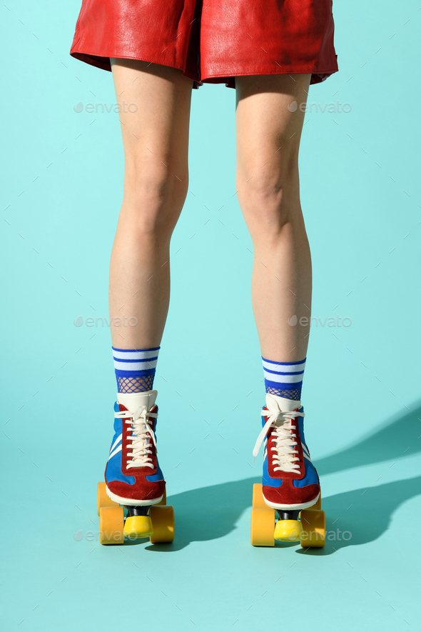 Legs of a slender sporty woman wearing multicolored roller skates - Stock Photo - Images