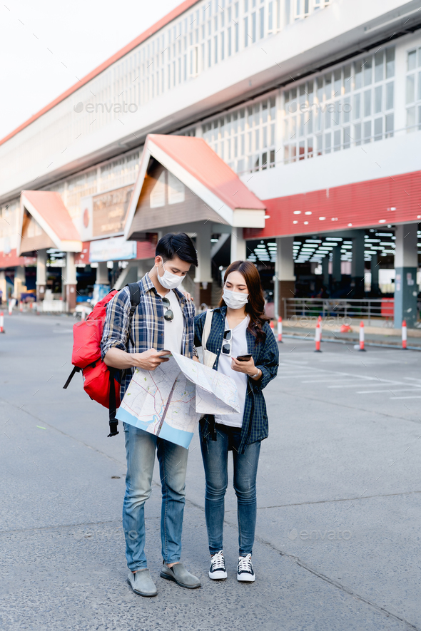 Young backpacker couple in mask checking location on paper map - Stock Photo - Images