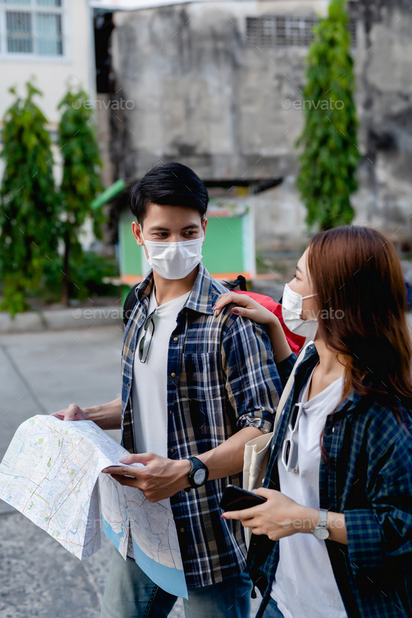 Young backpacker couple in mask checking location on paper map - Stock Photo - Images