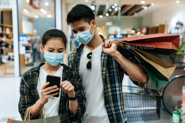 Young couple in mask holding multiple shopping paper bag - Stock Photo - Images