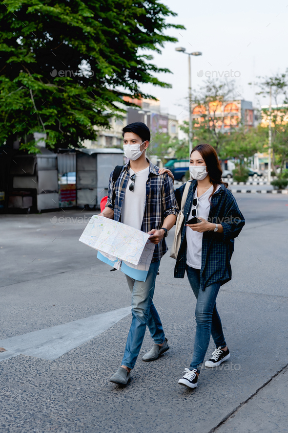 Young backpacker couple in mask checking location on paper map - Stock Photo - Images