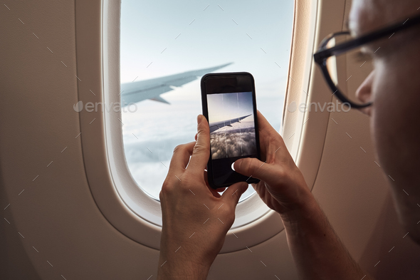 Passenger photographing through airplane window - Stock Photo - Images