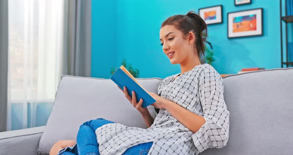 Beautiful Woman with Hair Pinned Up Relaxes in Homely Attire While Delving Into Book That alt