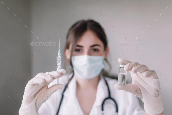 Doctor or nurse is holding glass vial bottle of anti virus vaccine and syringe