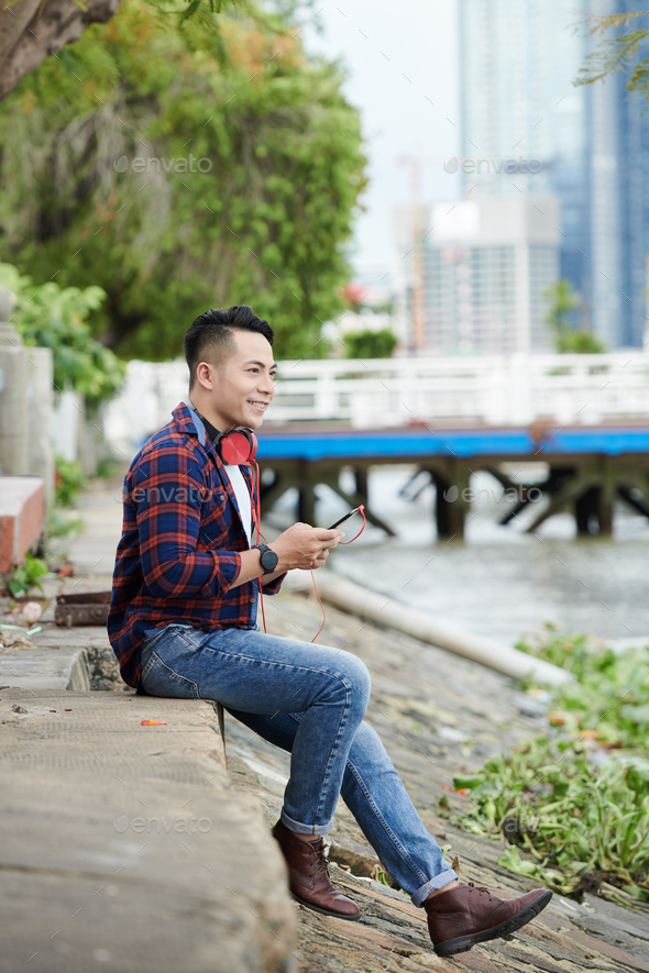 Dreamy Asian Man Choosing Track on Smartphone - Stock Photo - Images