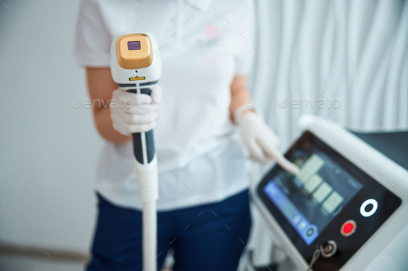 Certified dermatologist setting the treatment parameters on the laser machine - Stock Photo - Images