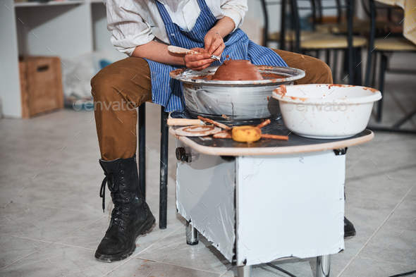 Pottery designer taking off clay from dish on electric wheel