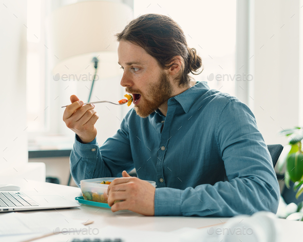 Hungry man enjoying vegan meal during lunch break - Stock Photo - Images