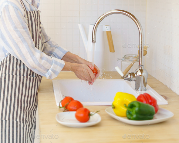 Faceless senior woman in apron preparing vegetables for salad while cooking in modern kitchen at - Stock Photo - Images