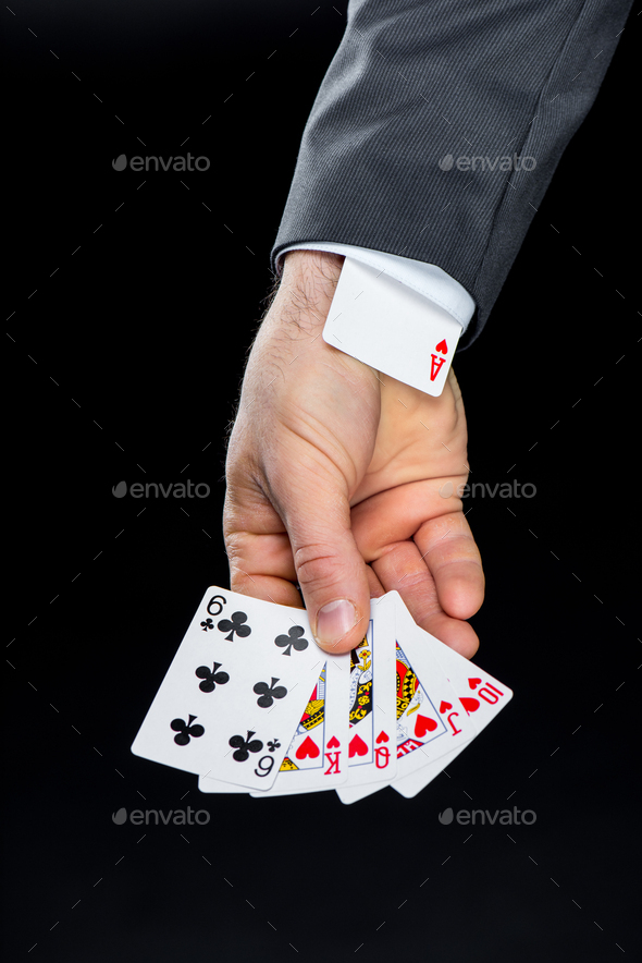 Partial view of man holding playing cards with hidden in sleeve ace of hearts isolated on black