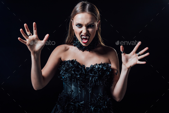 scary vampire girl with fangs in black gothic dress isolated on black ...
