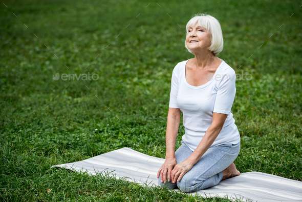 happy senior woman sitting in meditation pose with hands on knees and ...