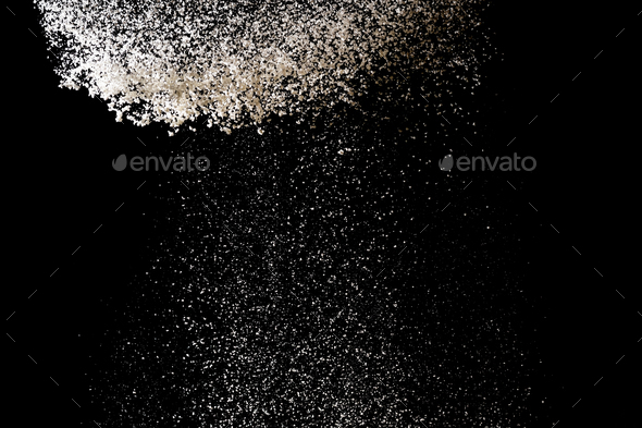 Flour sifting on a black background. White powder splash