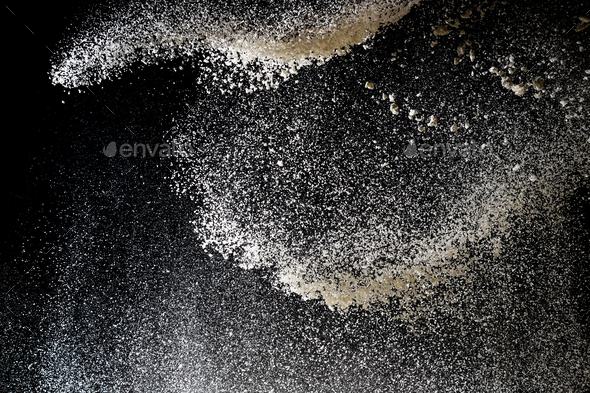 Flour sifting on a black background. White powder splash isolated on black background