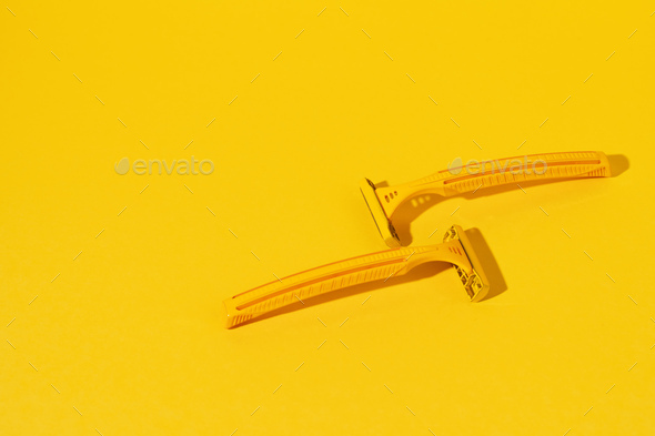 Disposable razors on yellow background, studio shot