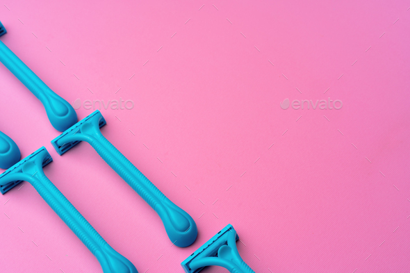 Female disposable razors on pink background top view