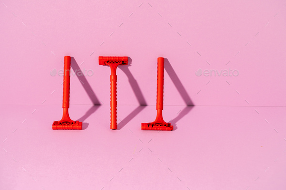 Red disposable razor on pink background, copy space