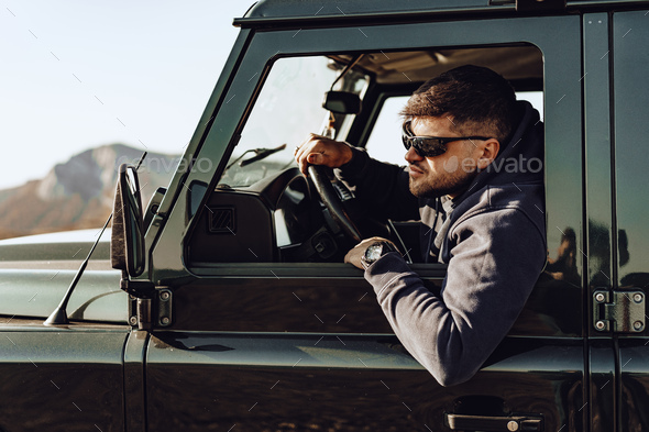 Male driver of an off-road car looking through the window - Stock Photo - Images