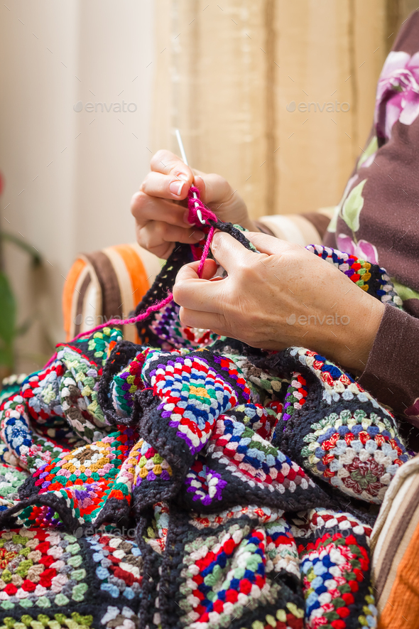 Hands of woman knitting a vintage wool quilt