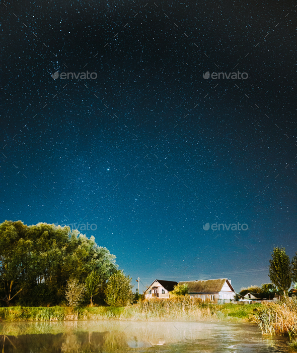 Evaporation Over River Lake Near Houses In Village. Milky Way Galaxy In Night Starry Sky Above Lake - Stock Photo - Images