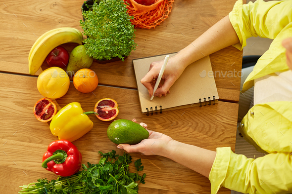 Woman planning, writing weekly meals on a meal planner note or diet plan - Stock Photo - Images