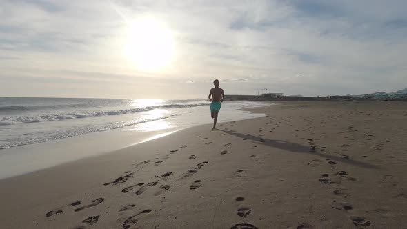 One young man running and enjoying summer in a beach alone with sunset alt