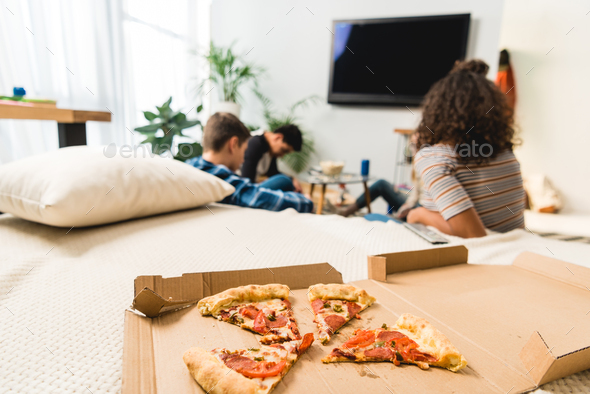 friends watching tv with pizza on foreground