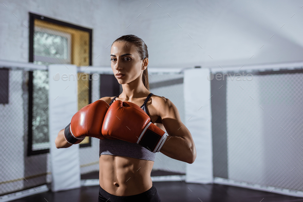 athletic young woman in boxing gloves looking at camera