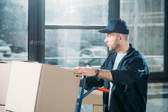 Loader man adjusting cardboard boxes on cart