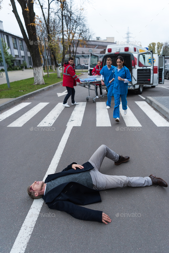 paramedics running to help injured man lying on a street