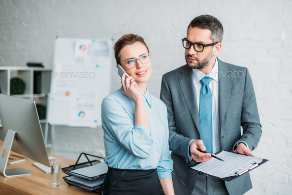 businessman asking his colleague to sign papers while she talking by phone and annoying him