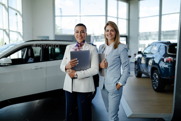 Two consultants or managers in elegant suit with laptop in arms, looking on camera with smile. - Stock Photo - Images