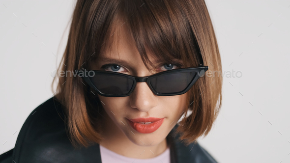 Beautiful blue eyed girl with short haircut and red lips wearing sunglasses  looking in camera Stock Photo by garetsworkshop