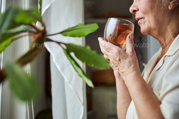 Elderly woman drinking herbal tea at home