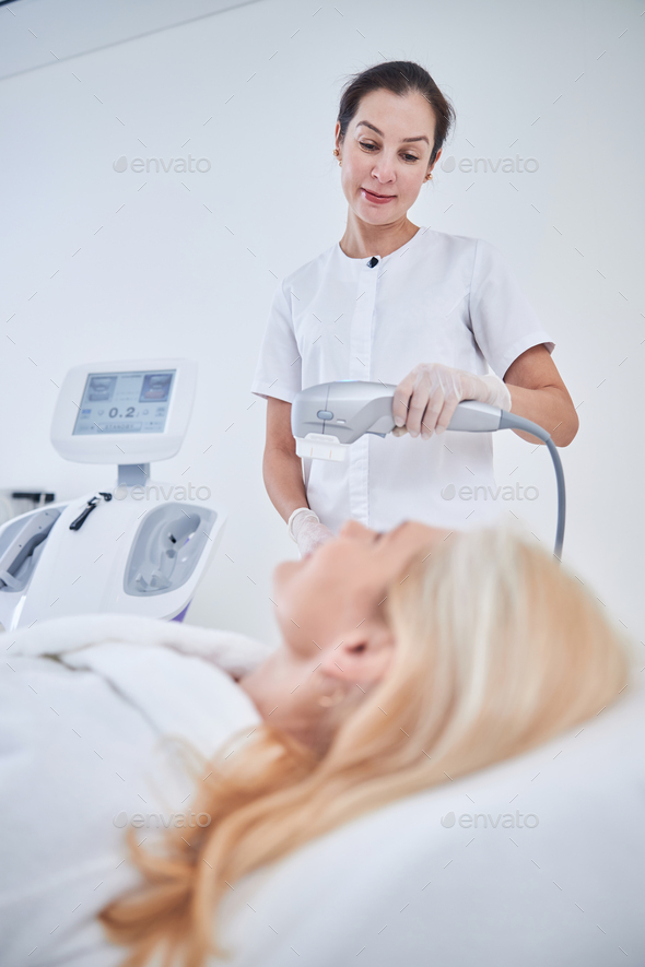 Elegant stylish brunette woman holding modern ultrasound machine above