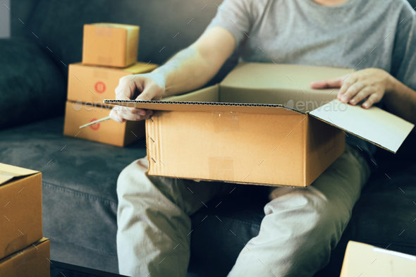entrepreneur teenager is opening a cardboard box in order to put the product that the customer - Stock Photo - Images