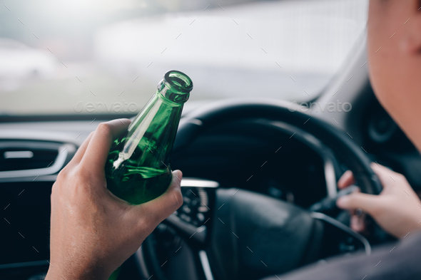 Asian men are breaking the traffic rules by holding a bottle of beer and drinking while driving.