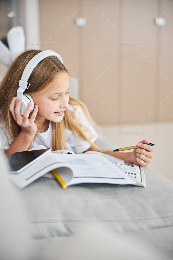 Underage student enjoying the tunes during a work with dictionary