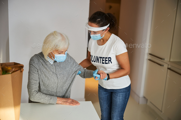Attentive caregiver helping a pensioner to her feet