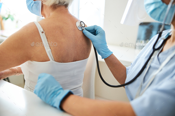 Physician putting a stethoscope resonator to a person shoulder blade