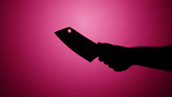 Man Holding Knife Axe Closeup Shadow Silhouette of Hand with Weapon on Pink Neon Background alt