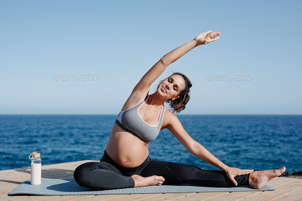 Young pregnant woman doing yoga on the beach - Maternity and